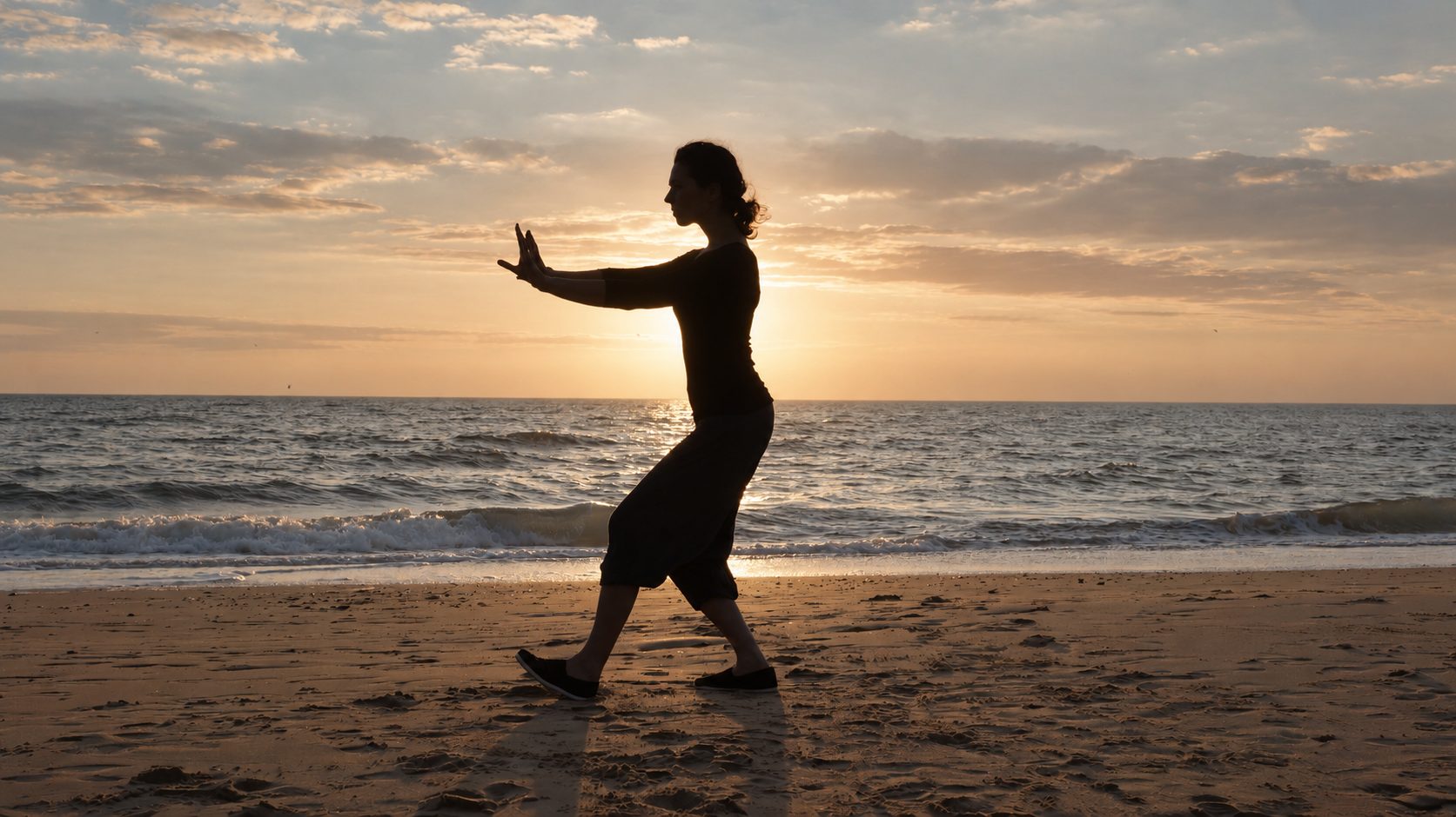 Wendy-Joyce doet Tai Chi op het strand bij zonsondergang