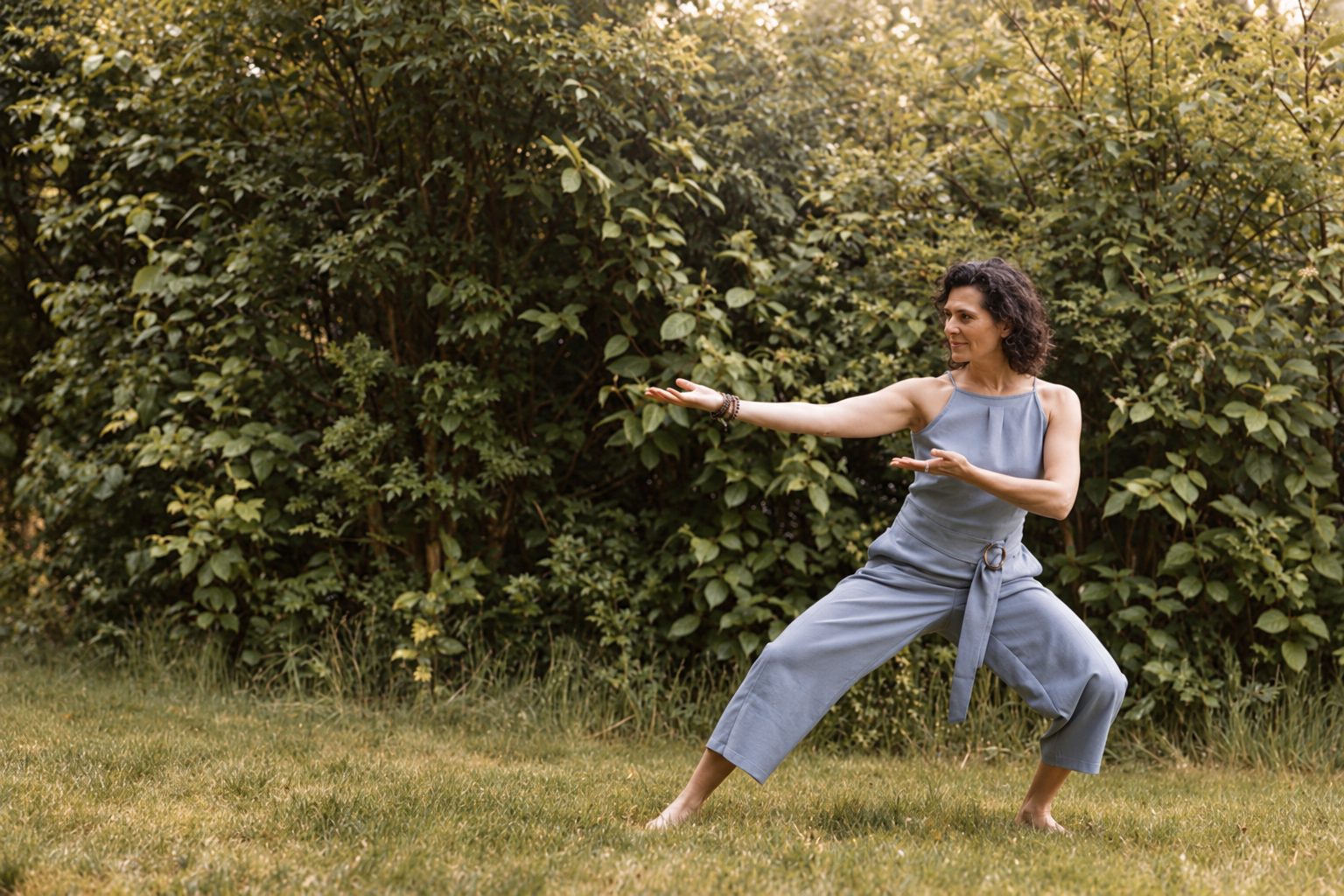 Wendy-Joyce in een Qigong-houding in een groene tuin